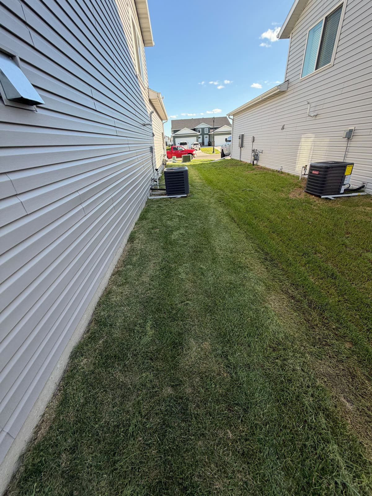 Mowed side yard between two homes showing detailed trim work